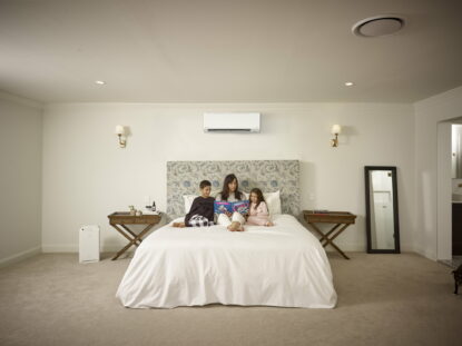 A photo of mother with her son and daughter reading a book in beautiful bedroom with multi split air conditioning system